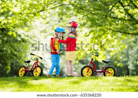 Children riding balance bike. Kids on bicycle in sunny park. Little girl and boy ride glider bike on warm summer day. Preschooler learning to balance on run bicycle in safe helmet. Sport for kids
