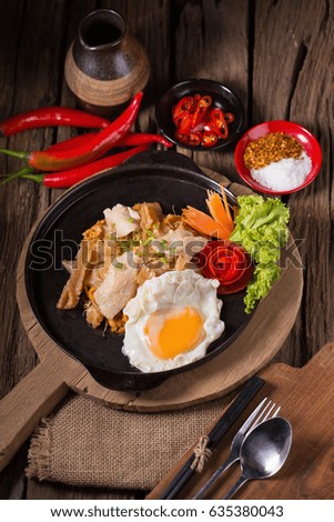 Asian noodles with fresh green onion and fried egg on old wood table.