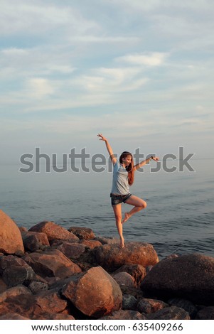 Beautiful girl poses on the stones near the sea at Sunset beach