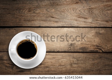 Top view of a white coffee cup on wood background.