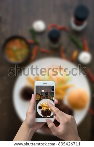Man hand taking photo steak with a smartphone, Top view pork steak set griled with bbq suace.