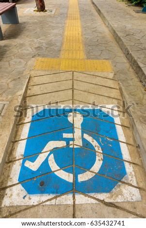 Handicap symbol on road, traffic and pedestrians in background
