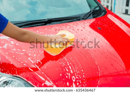 Man hand with yellow sponge washing car