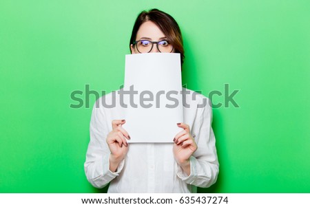 portrait of beautiful surprised young woman holding paper on the wonderful studio green background