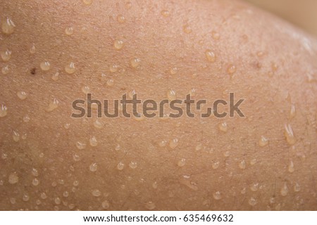 Close up of sweat or water drops on surface of woman arm skin, Sweat release from sweat gland for evaporation body heat. Show concept of skin tanned by sun light. Royalty-Free Stock Photo #635469632