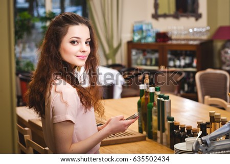 Young beautiful girl looks at the her phone at home in the kitchen
