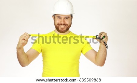 Cheerful construction engineer or architect in yellow tshirt and hard hat using measure tape against white background