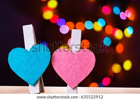 Blue and pink hearts on a clips against colorful bokeh background. Love and togetherness abstract concept.
