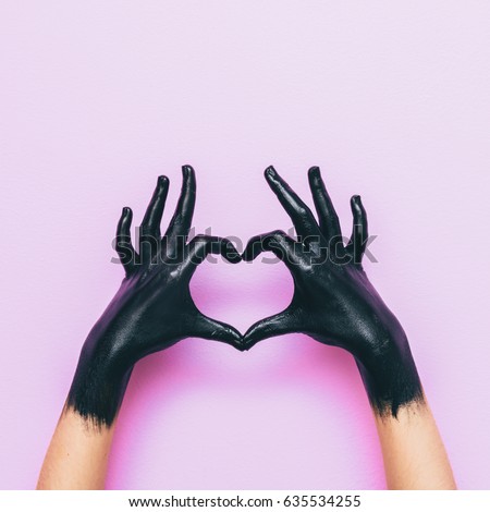 hands in black paint send heart. love and minimal fashion concept.