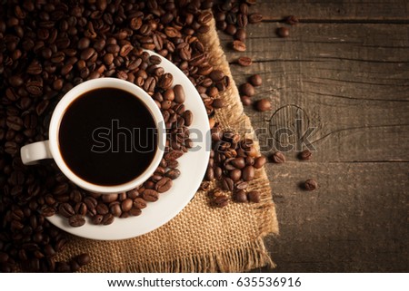 Coffee cup and beans on a rustic background. Coffee Espresso and a piece of cake with a curl. Cup of Coffee and coffee beans on table.