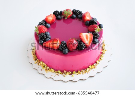 Mousse cake with pink mirror glaze and with berries, pistachios. Picture for a menu or a confectionery catalog.