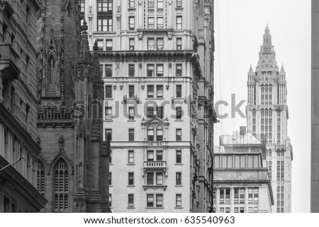 New York City, Lower Manhattan, arhitectural detail of Broadway street wiev: Trinity Church, New York City Charter School Center and Woolworth building far away. Black and white vintage image.