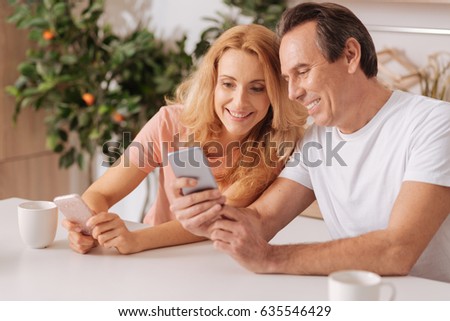 Cheerful couple using digital gadgets at home Royalty-Free Stock Photo #635546429