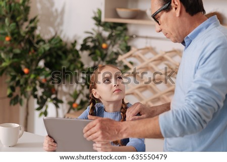 Decisive grandfather offspringing young granddaughter at home Royalty-Free Stock Photo #635550479