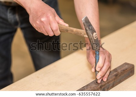 Male hands of builder man holding hammer and scored. Closeup photo