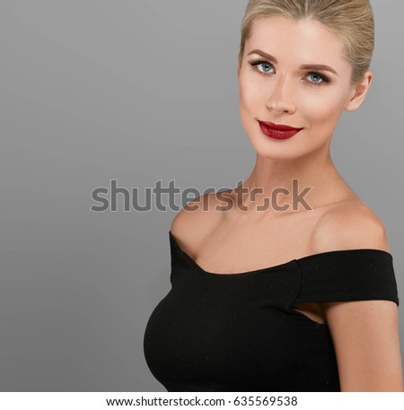 Blonde beautiful woman model over gray background. Woman nail manicure lipstick same color beauty portrait beautiful care