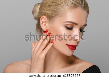 Blonde beautiful woman model over gray background. Woman nail manicure lipstick same color beauty portrait beautiful care