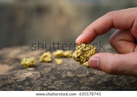 The pure gold ore found in the mine is in the hands of men. Royalty-Free Stock Photo #635578745