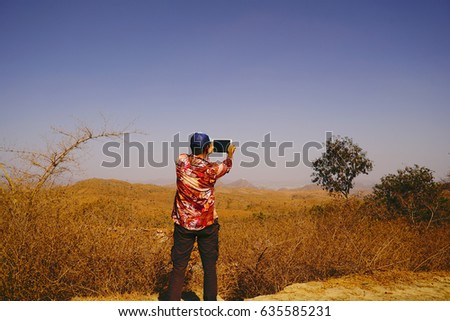 Man taking picture shot of castle on mountain on tablet in highlands. Near Udaipur. Rajasthan. India.