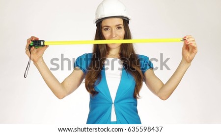 Beautiful female construction engineer or architect using measure tape against white background
