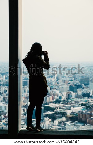 Woman silhouette taking a photo at Observation Deck. Filtered image.