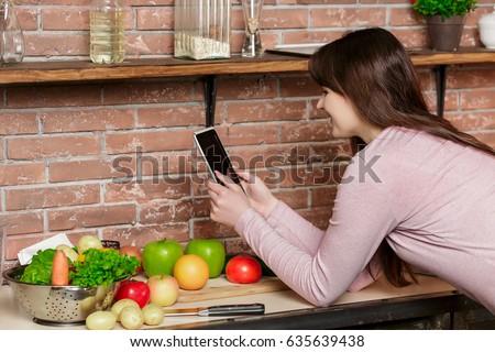 happy woman cooking on kitchen.Woman uses a tablet for online shopping and searching for recipes in the kitchen.