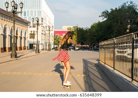 summer holidays, extreme sport and people concept - happy girl riding modern skateboard on city street