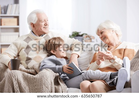 Older grandparents reading a book to their young grandson Royalty-Free Stock Photo #635650787