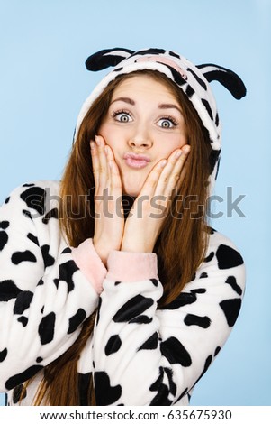 Happy teenage girl in funny nightclothes, pajamas cartoon style making silly face, positive face expression, studio shot on blue.