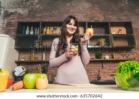 Woman holding a glass of orange juice in the kitchen. The concept of a healthy diet. Diet.