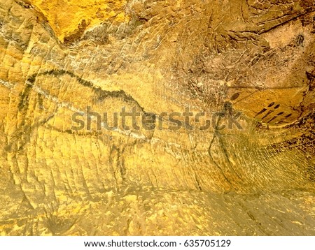 Buffalo hunting. Paint of human hunting on sandstone wall, prehistoric picture. Black carbon abstract children art in sandstone cave. Spotlight shines on caveman painting in cave