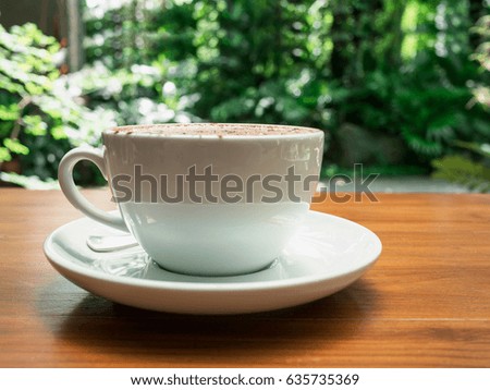 hot coffee cup on the wood table with bokeh nature background.