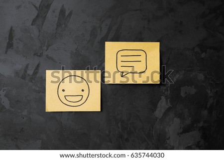 handwriting of smiling face with drawing of chat message icon on a sticky note paper on abstract concrete wall