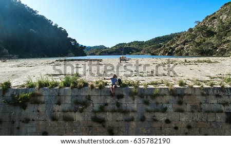Man traveler sitting on a edge of the dam and taking selfie photo. Aerial photography. Photo was taken in The Tibi Dam (embalse de Tibi). It is one of the oldest dams in Europe. Spain