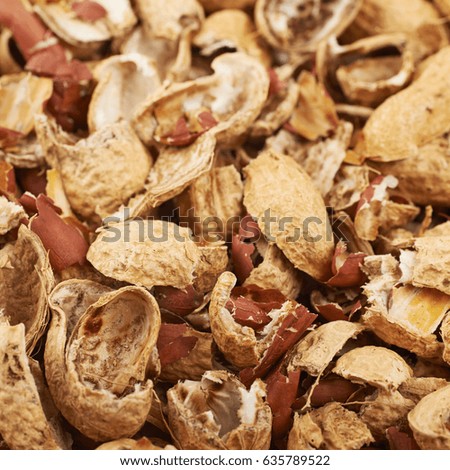 Close-up crop of a surface coated with the peanut shells as a food backdrop composition with a shallow depth of field