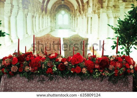 Garland of peonies lies on dinner table with candles