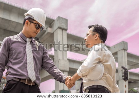Two businesspeople shake hands and congratulate them on their success.