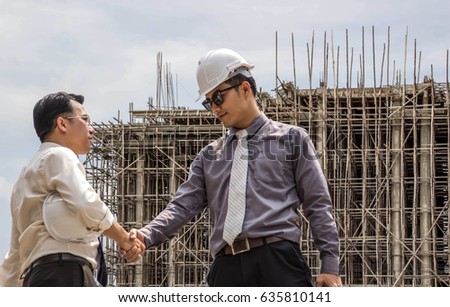 Two businesspeople shake hands and congratulate them on their success.