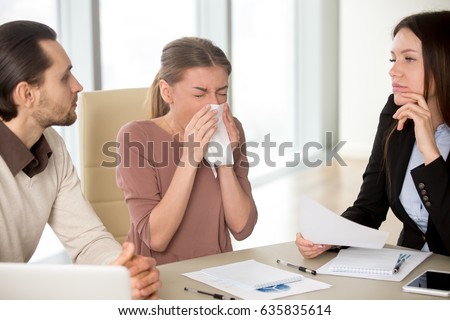 Sick young attractive woman with handkerchief has sneezing attack, blowing nose while working with colleagues on meeting, caught cold, flu symptom, weakened immune system due to stress or overwork Royalty-Free Stock Photo #635835614