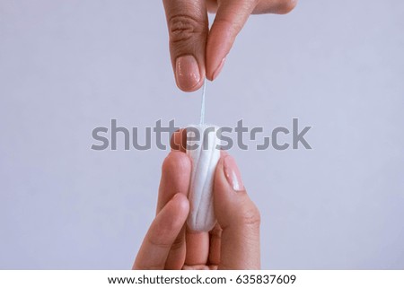 Woman's hand holding clean cotton tampon close-up.  