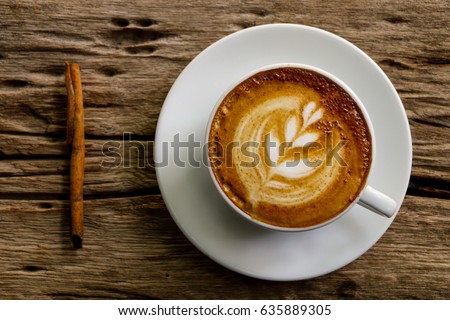 Hot cofffee cup on wooden with painting leaf