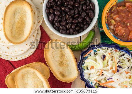 Top view of bowl with black beans, mini taco boats, cabbage, salsa - ingredients for taco with black beans and vegetables.