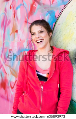 Fit young woman leaning on graffiti wall