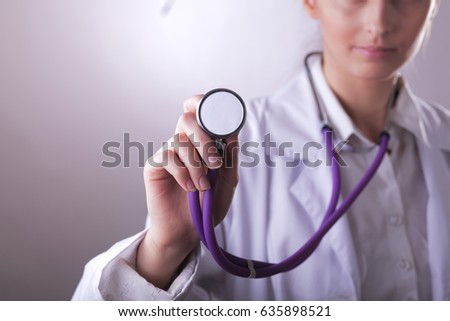 A young female doctor listening ,holding medical stethoscope
