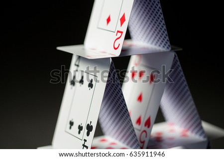 casino, gambling, games of chance, hazard and insecurity concept - close up of house of playing cards over black background
