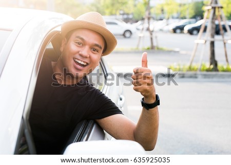 Young asian man showing thumbs up while driving car Royalty-Free Stock Photo #635925035