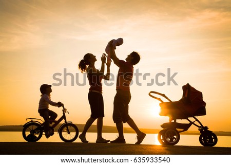 Silhouettes of parents walk with small children with a stroller