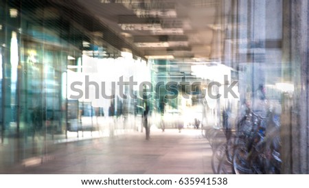 Abstract, blurred image of people walking via long tunnel with light at the background.