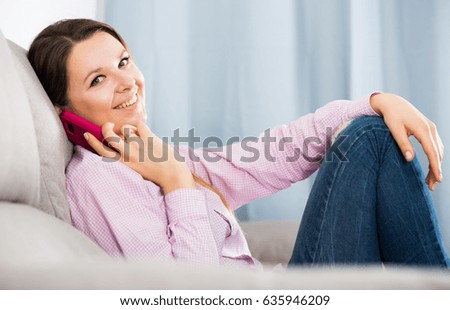 Smiling girl texting with her phone and taking photos at home