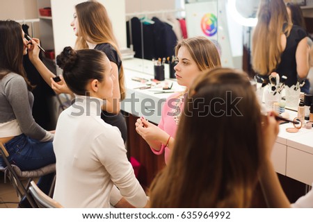 Three professional make-up artists work with beautiful young women. School of professional make-up
